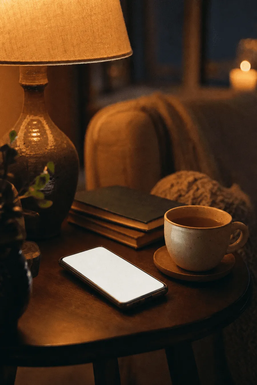 A phone glowing softly beside a warm lamp in the evening